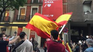 Un grupo de personas se manifiestan ante la sede del PSOE, protegida por la Policía Nacional, por la gestión de la crisis sanitaria, este domingo 17 de mayo.