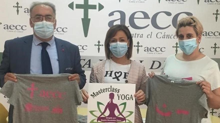 María Hernández, presidenta de la AECC, presenta el cartel de la actividad con los patrocinadores de las camisetas