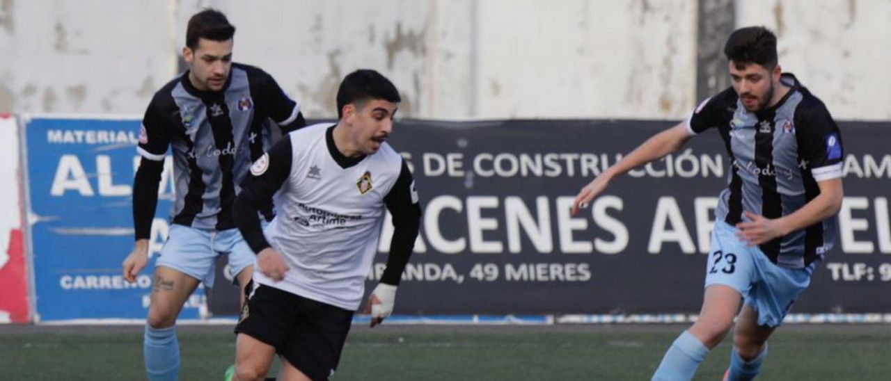 Carlos Cid conduce el balón ante dos defensores del Tuilla. | F. Rodríguez