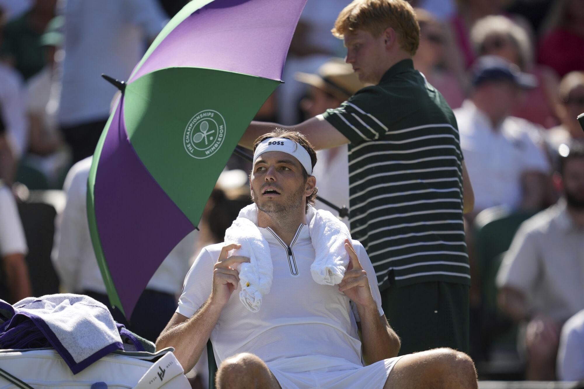Taylor Fritz of the U.S. tries to keep cool in a break in his match against Spain's Carlos Alcaraz in a men's singles semifinal at the Wimbledon Tennis Championships in London, Friday, July 11, 2025. (AP Photo/Kin Cheung)