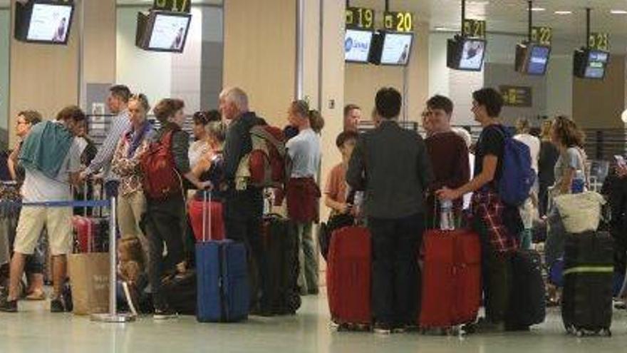 Cola de turistas frente a un mostrador de facturación en el aeropuerto de Ibiza.