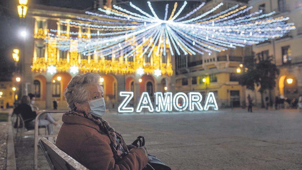 Una señora con mascarilla sentada en un banco de la Plaza Mayor. 