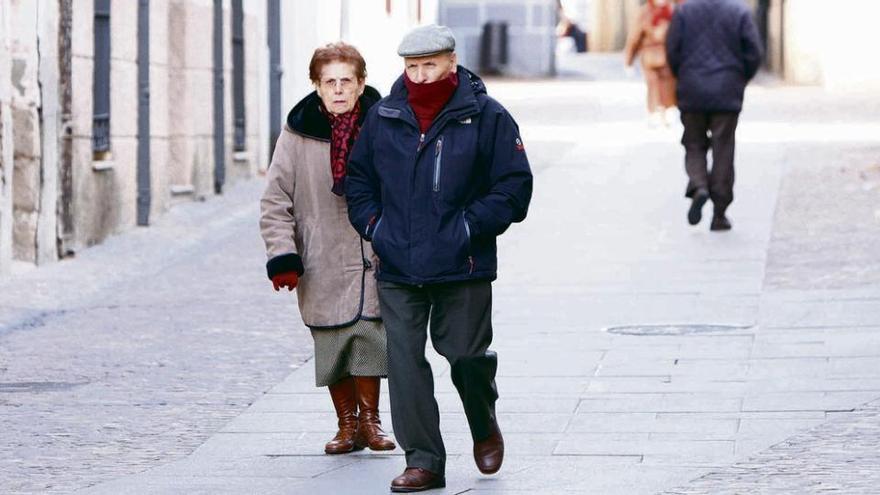Una pareja se resguarda del frío con guantes y bufandas durante un paseo matutino.
