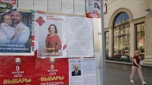 Una mujer pasa junto a unos carteles electorales de los principales candidatos en Minsk.