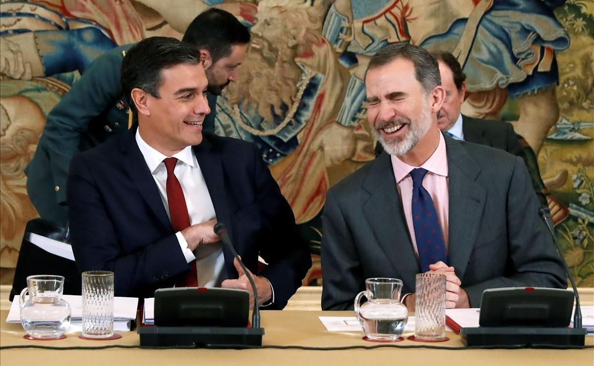 El rey Felipe VI y el presidente del Gobierno, Pedro Sánchez, no pueden evitar la risa durante la XXX sesión ordinaria del patronato de la Fundación Carolina, este lunes, en el Palacio de la Zarzuela.