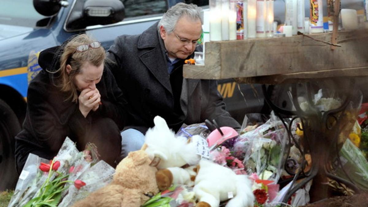 Ciudadanos de Newtown rezan ante el memorial popular en recuerdo de las víctimas del tiroteo ante la iglesia católica de Santa Rosa de Lima.