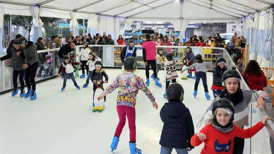 Niños y adultos patinando en la pista de hielo sintético de Ponteareas en la Praza Maior. // A. Hernández