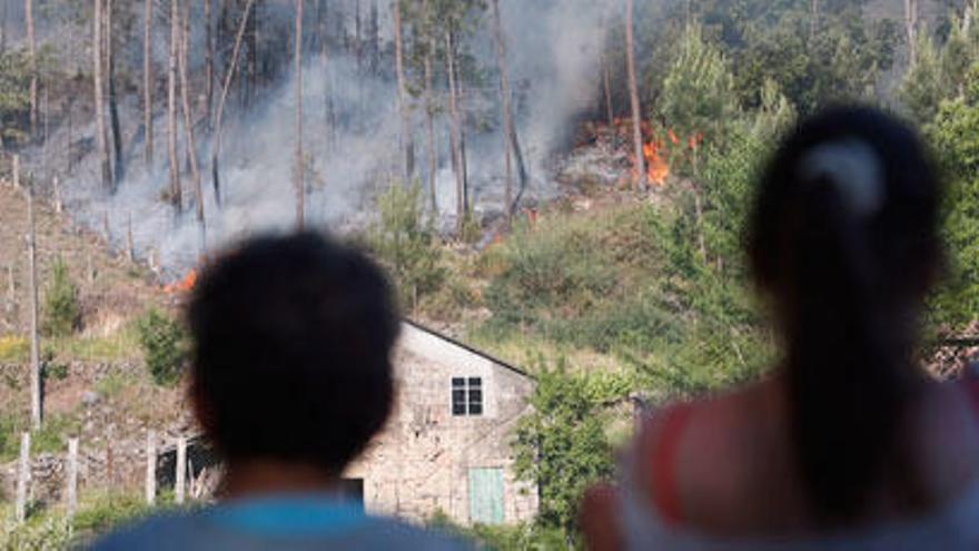 Dos vecinos observando el incendio que afecta a la parroquia de Padróns // NICK