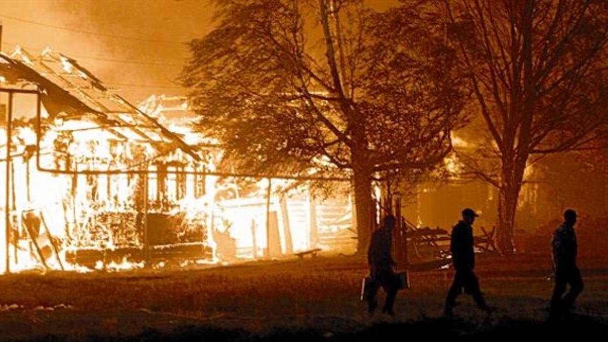 Dantesco 8 Tres hombres se alejan de una casa en llamas en el pueblo de Vyksa, a 150 kilómetros de Nizhny Novgorod.