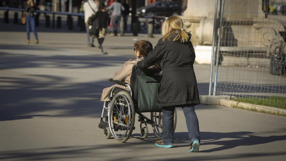 Una mujer acompaña a otra en silla de ruedas en Barcelona, el 30 de noviembre del 2015
