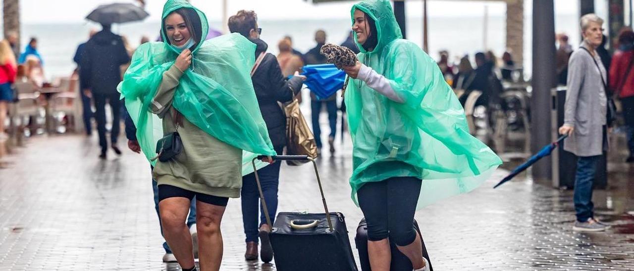 Turistas con maletas bajo la lluvia en Benidorm.