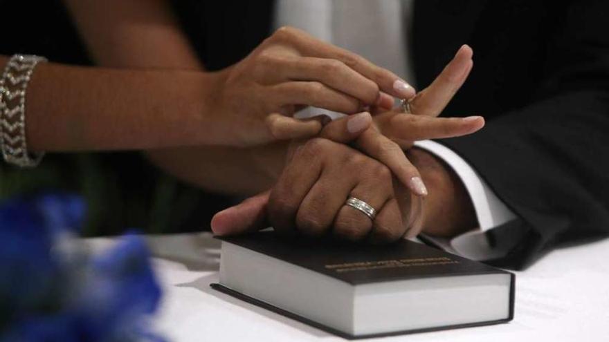 Una pareja de novios intercambia los anillos durante su boda.