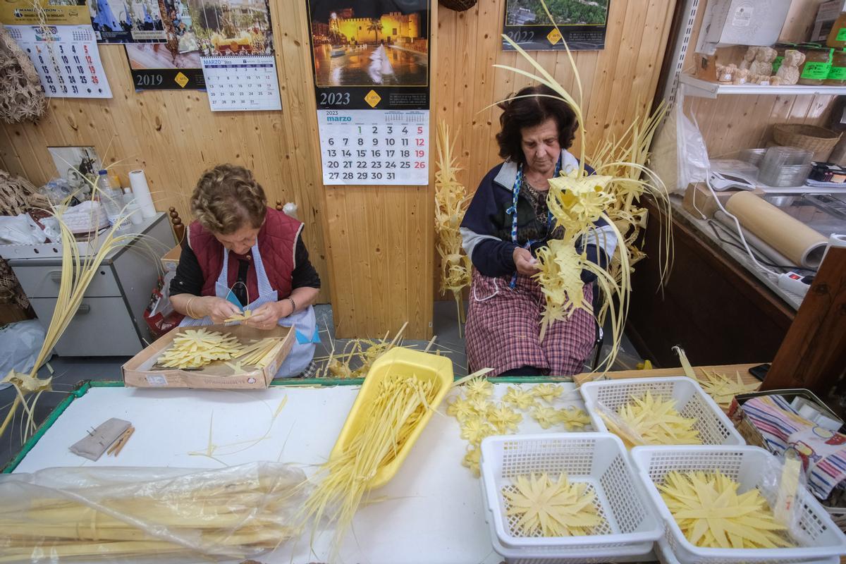 Mari Carmen y Ángela, con sumo cuidado, elaboran meticulosamente algunas palmas en el taller.