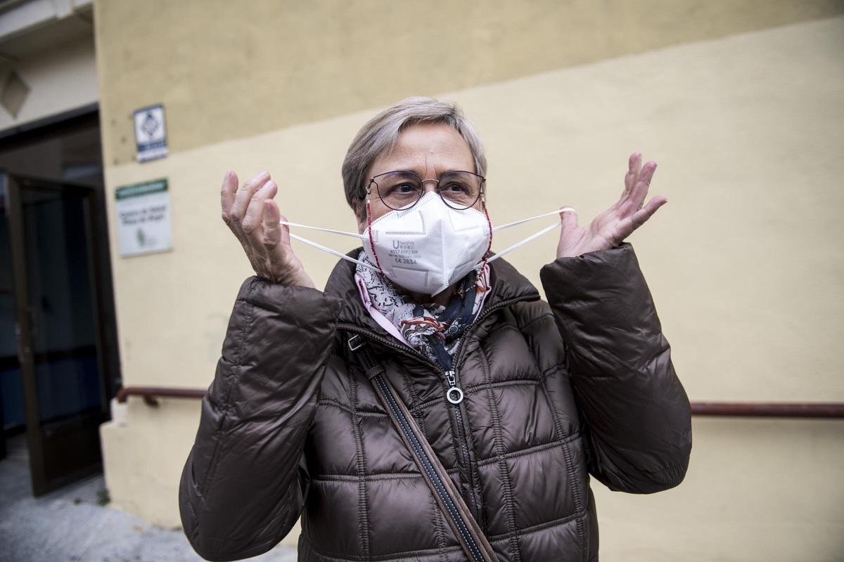 Una mujer se quita la mascarilla tras salir de un centro de salud de Cáceres con mascarilla, el primer día de uso obligatorio.