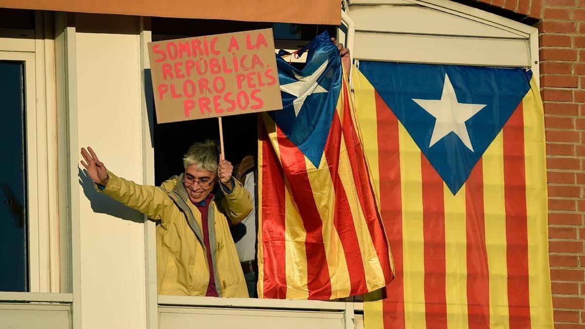 Una mujer exhibe una pancarta reclamando la libertad de los presos desde una ventana al paso de la manifestación.