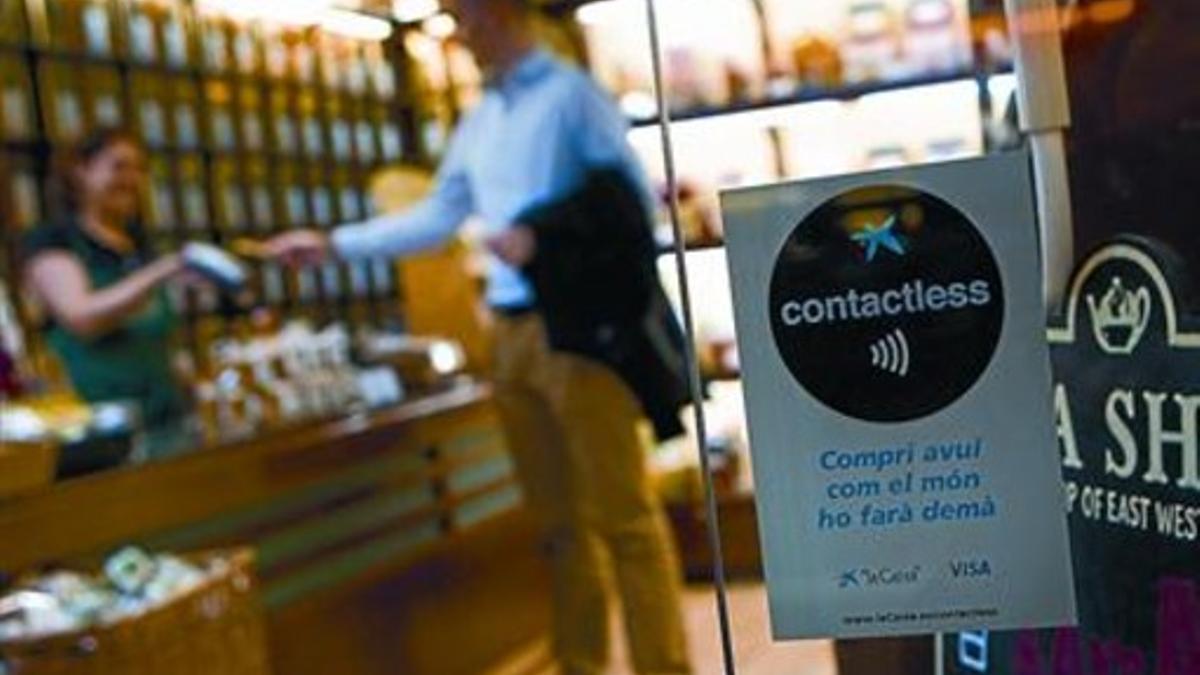 Un ciudadano paga con una tarjeta de crédito con chip NFC en una tienda de Barcelona.