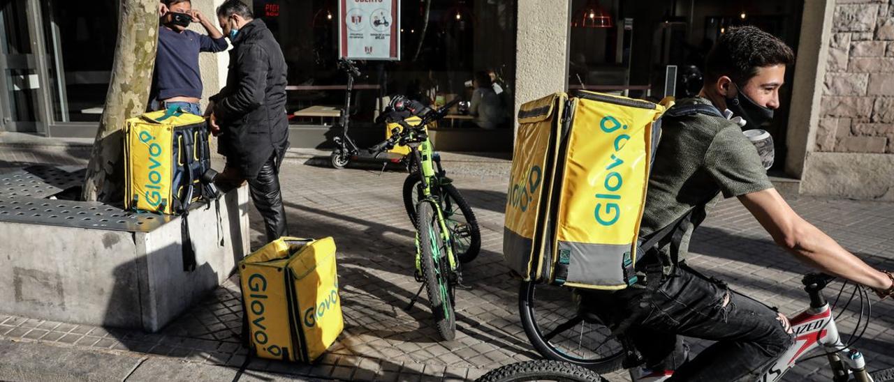 Repartidores de Glovo esperan su pedido a las puertas de una cadena de restaurantes de comida rápida.