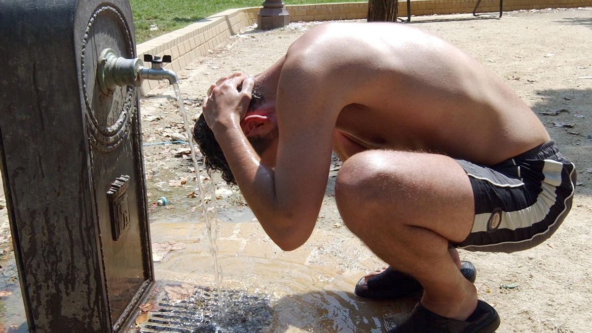Un joven se refresca en una fuente para tratar de mitigar las altas temperaturas.