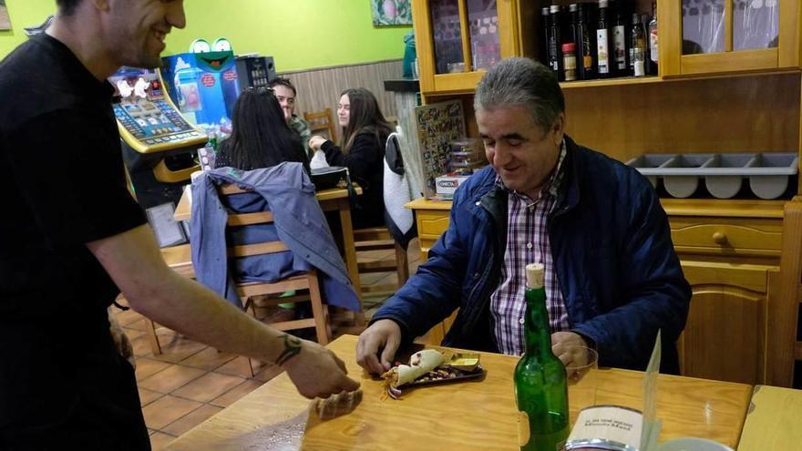 Abel Salazar, sirviendo un pincho a Alberto Núñez, ayer, en el bar Les Escueles.