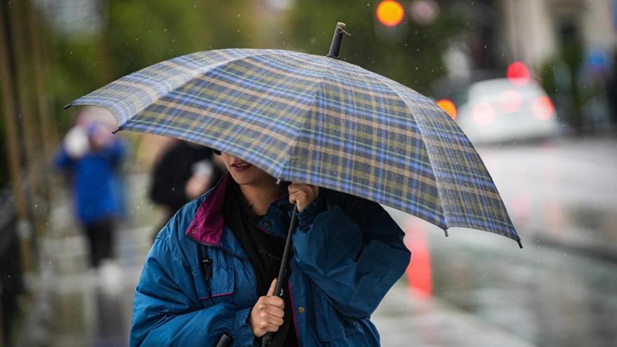 Una mujer se protege de la lluvia con un paraguas.
