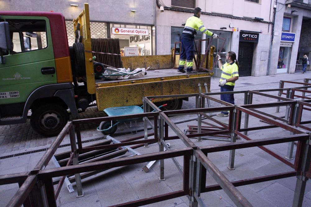 Carrers amb restes de mobiliari urbà cremat, contenidors per terra i treballadors de la brigada treballant