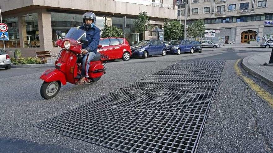 Dos &quot;trampas&quot; con diferentes soluciones |  En la Plaza Francisco Fernández del Riego, sobre el Centro Comercial Plaza Elíptica, existe otra rejilla de ventilación sobre el asfalto. Se trata de una peligrosa trampa para motoristas y ciclistas, especialmente si la superficie está húmeda. En este caso, el Concello optó hace varios años por delimitar este punto creando una falsa isleta para disuadir a los pilotos de que circulen sobre ella, aunque ahora está prácticamente borrada.