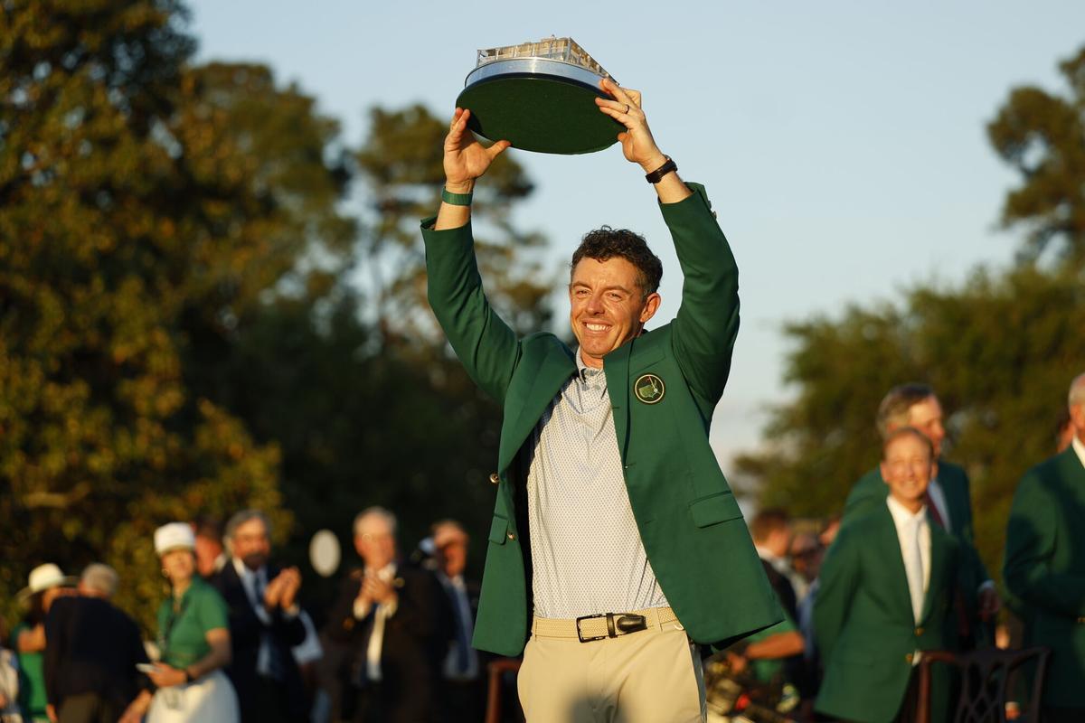 Rory McIlroy levanta el trofeo de campeón del Masters de Augusta con la chaqueta verde ya puesta.