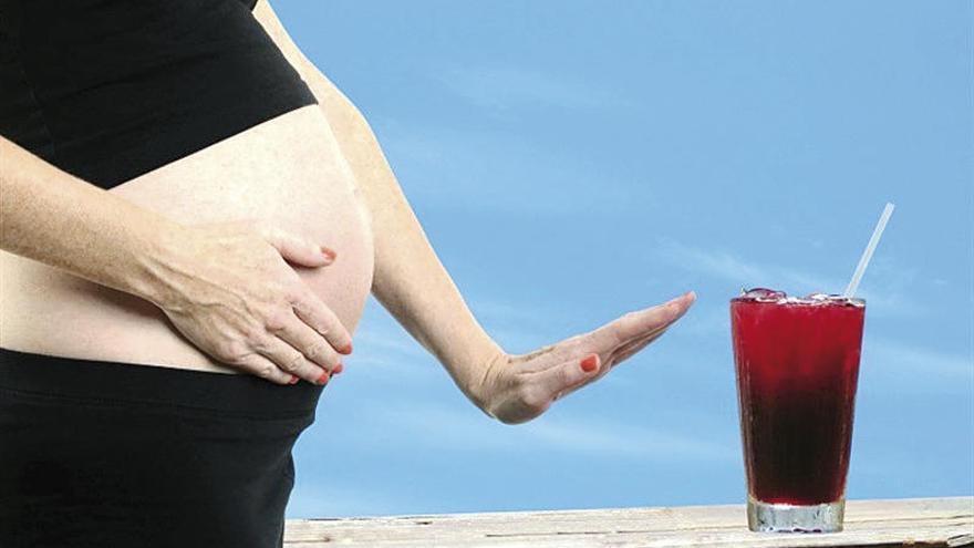 Una mujer embarazada junto a un cóctel.