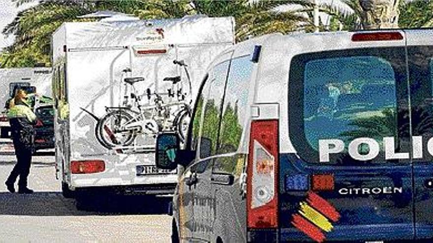 Una policía mira la autocaravana tiroteada junto al paseo marítimo del Port de Sagunt.