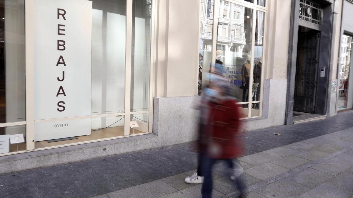 Gente caminando por la calle en plena campaña de rebajas en las tiendas.