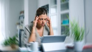 UNA MUJER SE PRESIONA LAS SIENES PARA ALIVIAR SU DOLOR DE CABEZA. Sick dizzy young woman suffering headache while working on her laptop at home. FOTO DE RECURSO. DOLENCIA. MIGRAÑAS. CEFALEAS. ESTRES