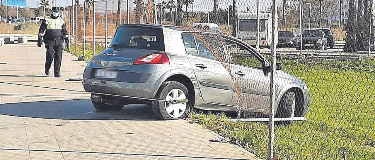 Un policía local, junto a un coche abandonado tras estrellarse contra una valla en Palma.