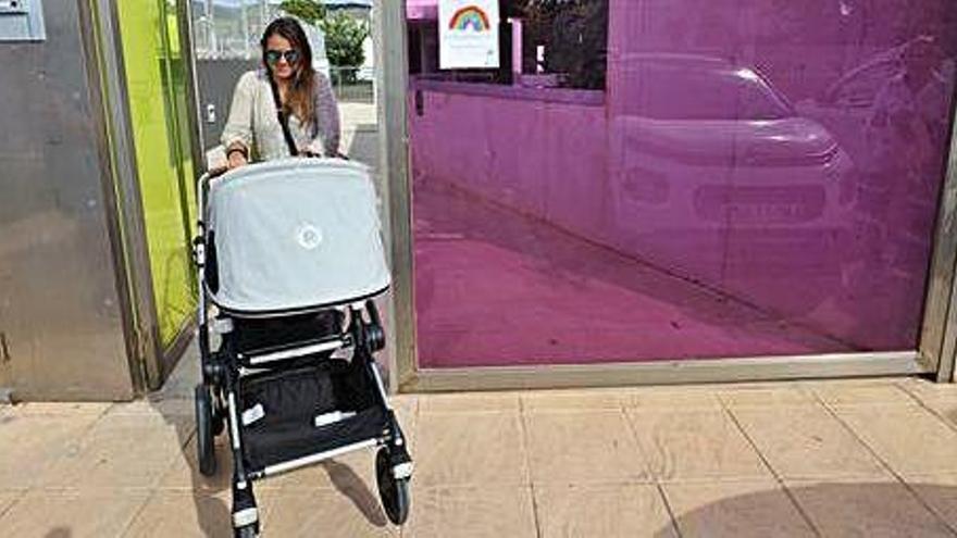 Una madre sale del centro con su carrito.