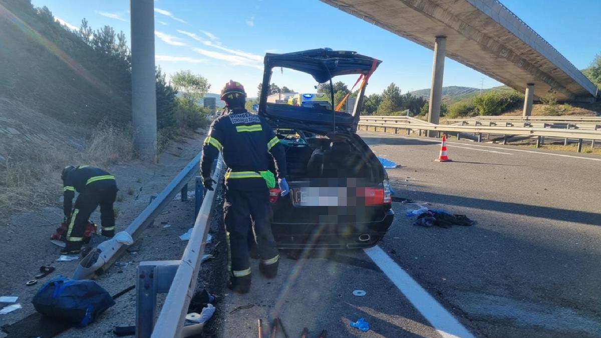 Los bomberos junto al coche después del siniestro.