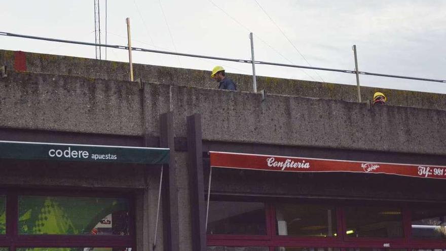 Dos obreros hacen trabajos en la cubierta de la estación de autobuses.