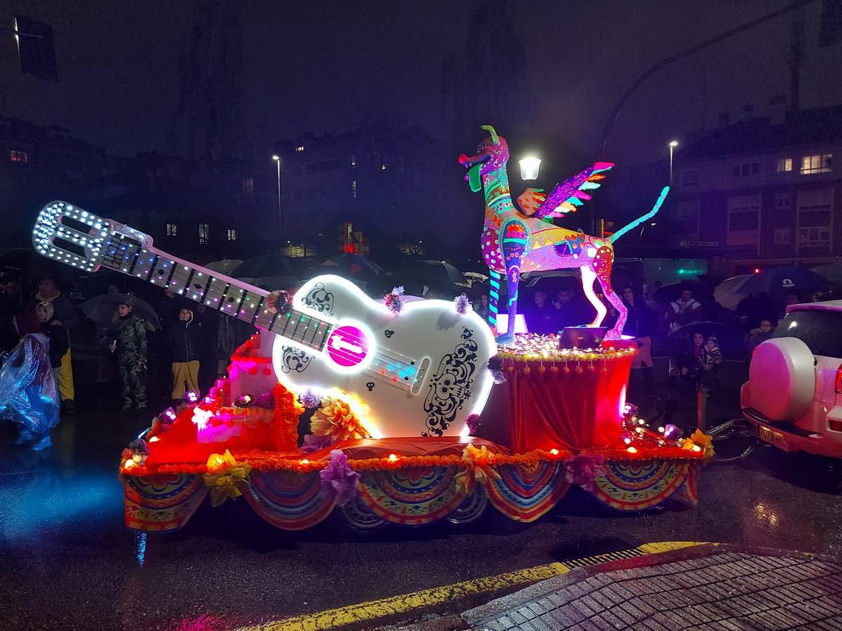 Una llamativa y musical carroza aparece en escena. La lluvia arrecia, pero el público no se mueve.