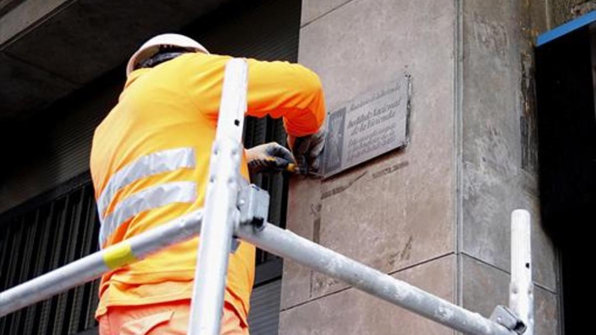 Un operario municipal retira una placa franquista en Barcelona, ayer.