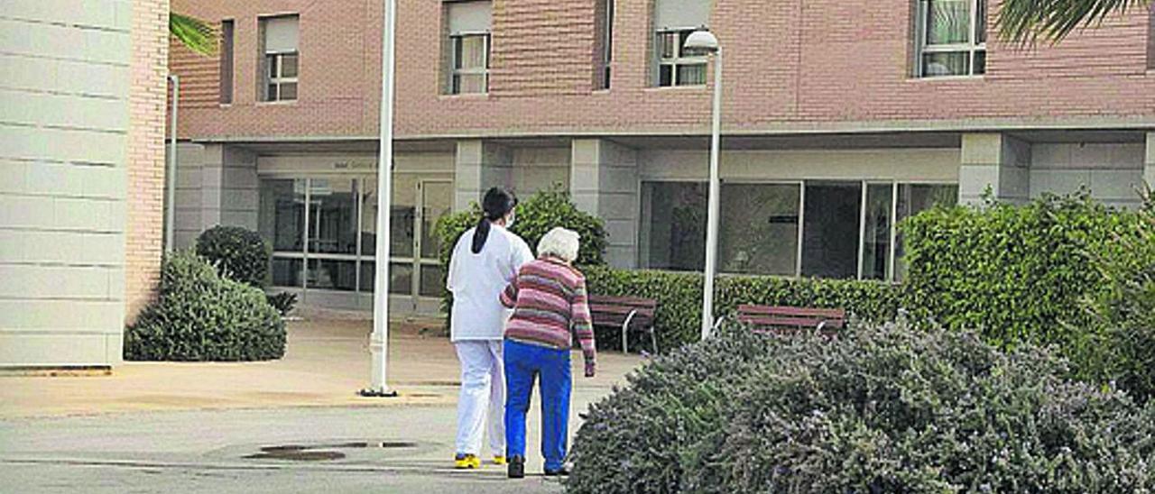 Una auxiliar de enfermería compañando a una residente de un geriátrico de Alicante.