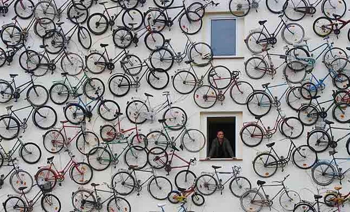 Un empleat de l’anomenada ’Estació de Bicicletes’ observa per la finestra de l’edifici que té la façana coberta amb bicicletes velles a Altlandsberg (Alemanya). La casa de lloguer de bicicletes i atracció turística té més de cent bicicletes a la paret.