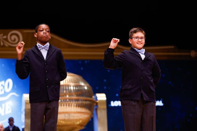 Los niños de la residencia San Ildefonso de Madrid Adam Lucas (d) y Sergio Abaga (i) muestran el número 37.876, un quinto premio dotado con 60.000 euros en cada serie, 6.000 euros al décimo, durante el Sorteo de la Lotería de Navidad que se celebra este domingo en el Teatro Real, en Madrid. EFE/Javier Lizón