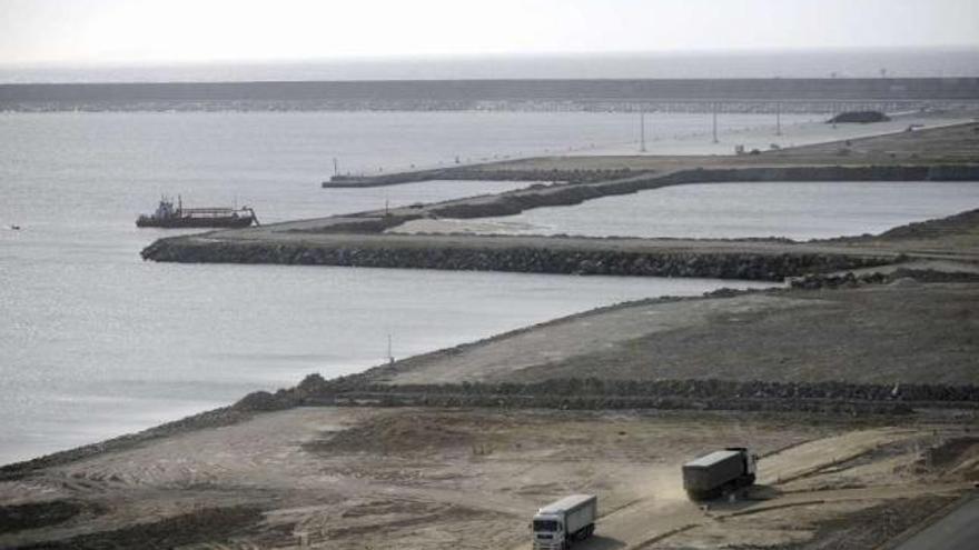 Dos camiones, ayer, en el puerto exterior, con un barco al fondo. / juan varela