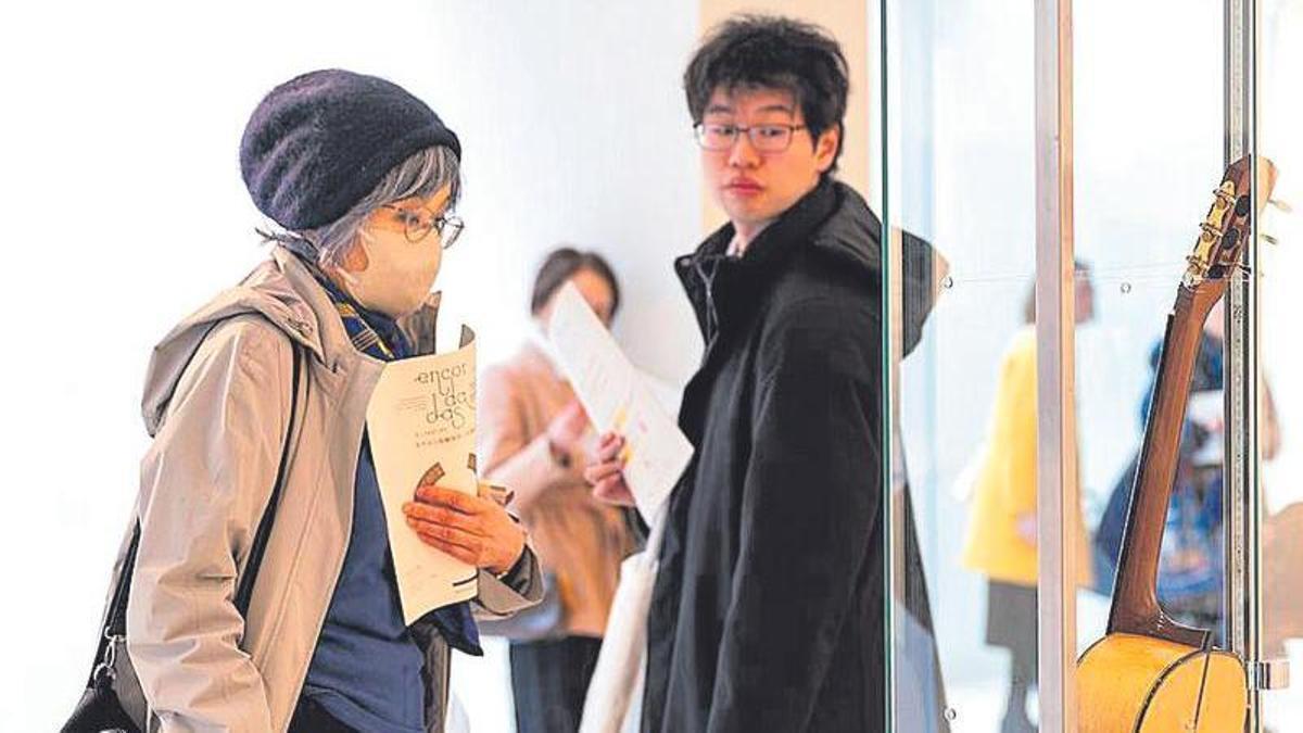 Algunos asistentes observan las piezas de la exposición.