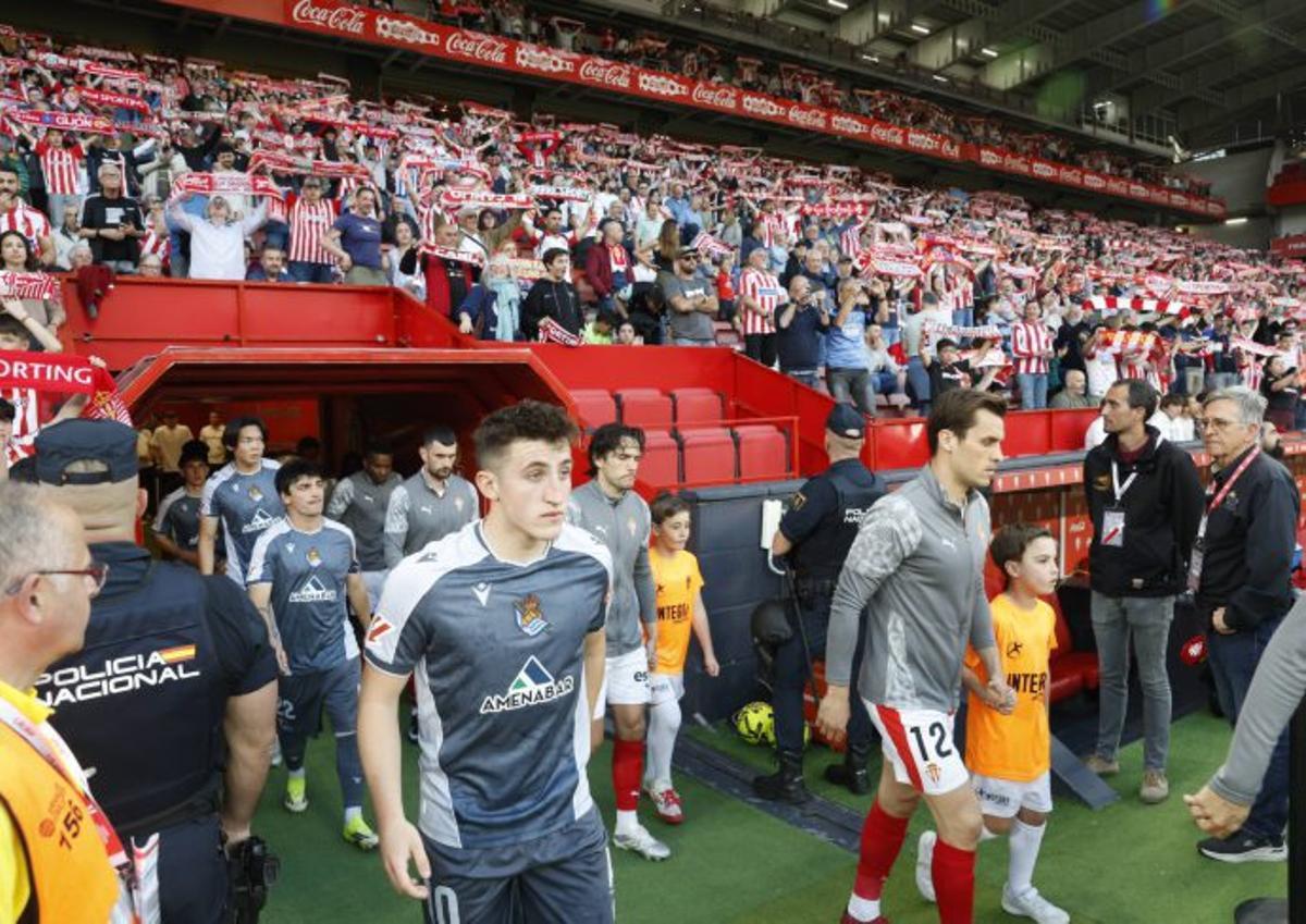 Jugadores saltando al campo con los aficionados de fondo. A la derecha, la atención médica.