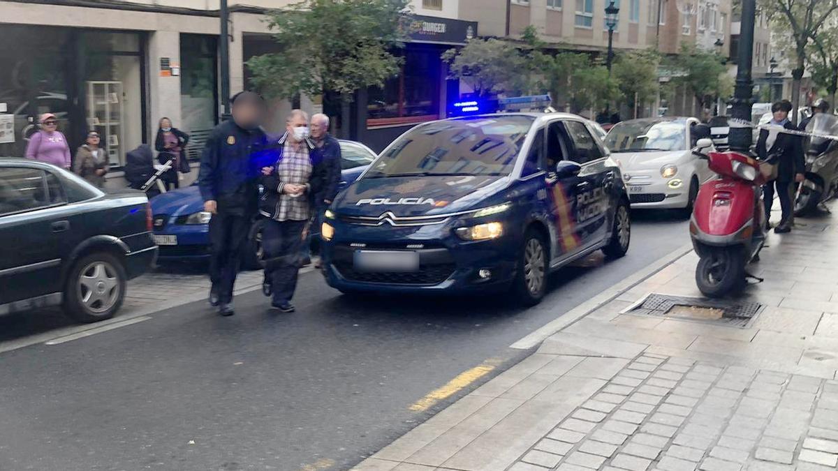 El presunto asesino de la calle Zamora vuelve, custodiado por un agente de la Policía, al lugar del crimen.