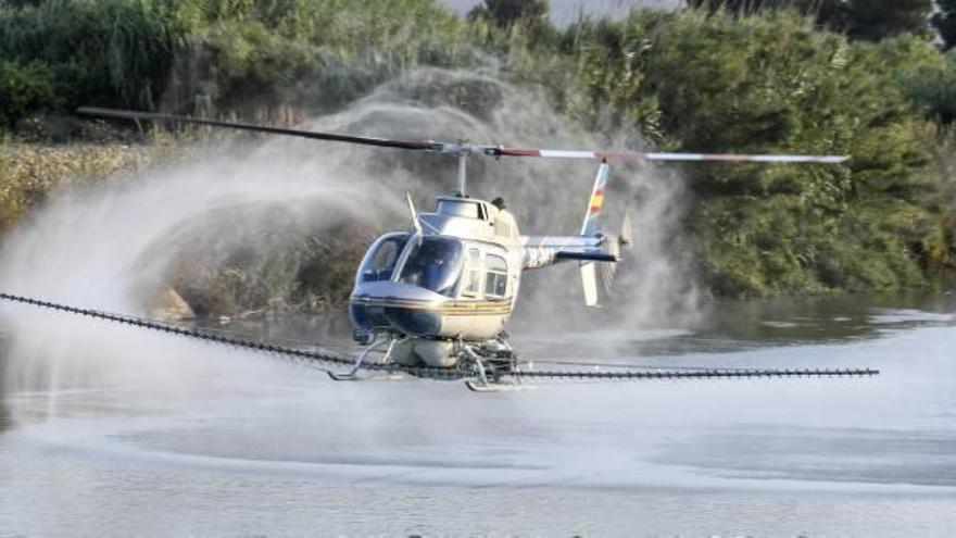 El helicóptero, durante una fumigación en el cauce del Xúquer a la altura de Riola, en el verano de 2017.