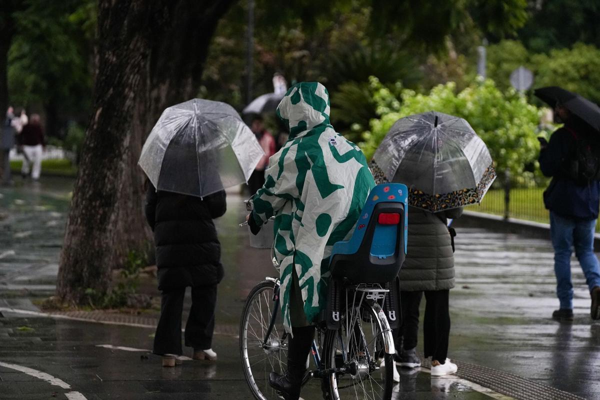 Sevillanos protegiéndose de la lluvia y el viento