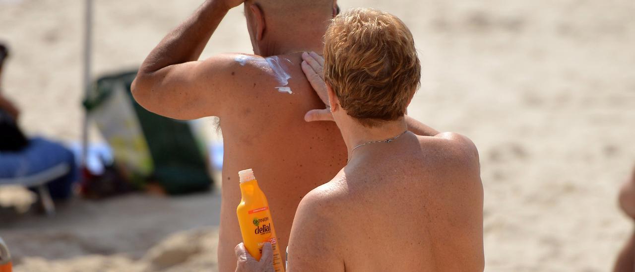 Dos bañistas se protegen del sol en una playa gallega.