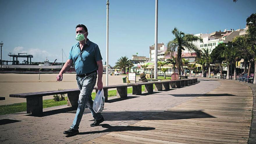 Un hombre con mascarilla camina por el Paseo de Los Cristianos (Arona).