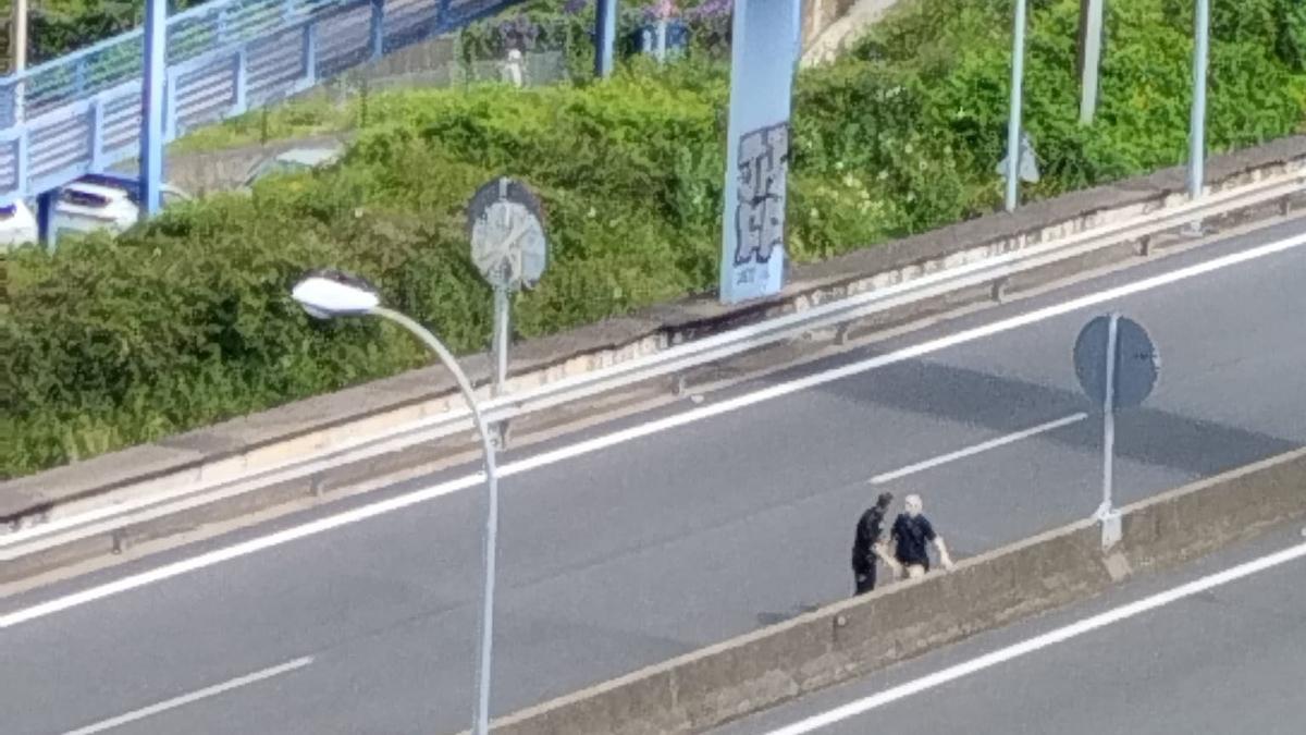 Un agente auxiliando al hombre en medio de la autopista