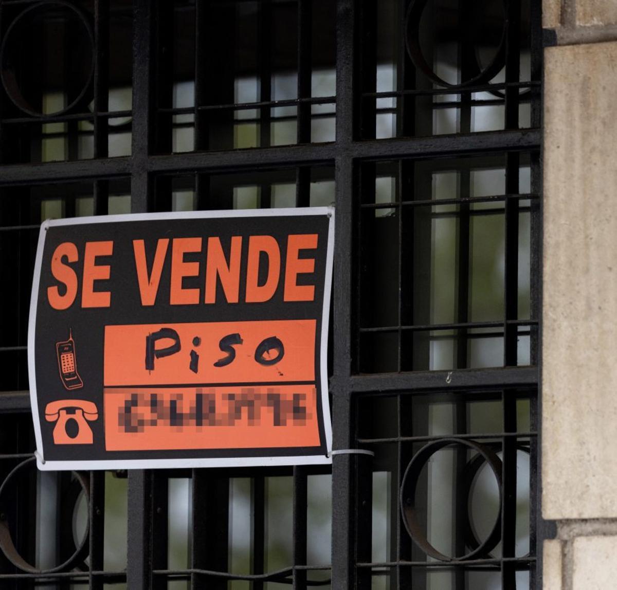 Vista de un cartel de «Se vende» en un portal de un edificio.